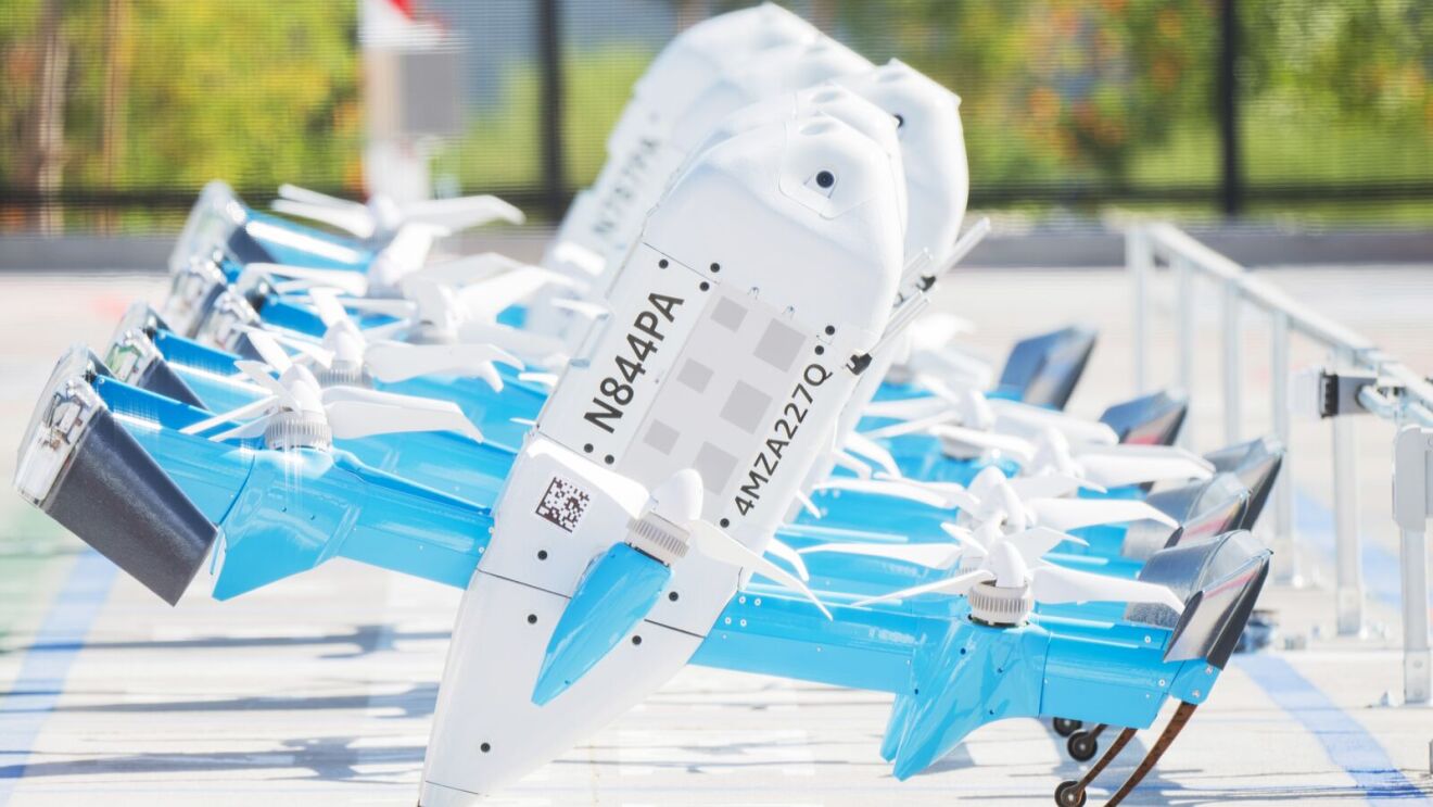Una fila de drones de reparto Amazon Prime Air MK30 con matrículas visibles en la cola.