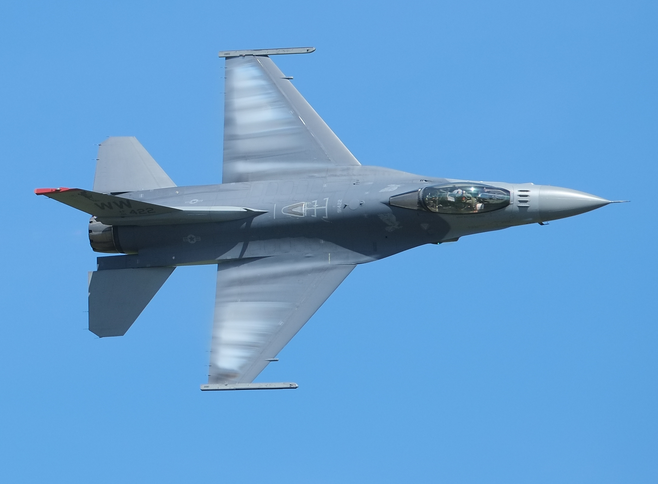 Un F-16 Fighting Falcon vire, des nuages de condensation se formant sur ses ailes.