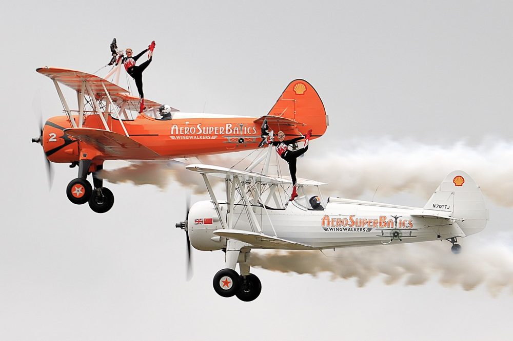 Deux acrobates aériens d'AeroSuperBatics réalisent des figures sur des biplans Boeing Stearman.