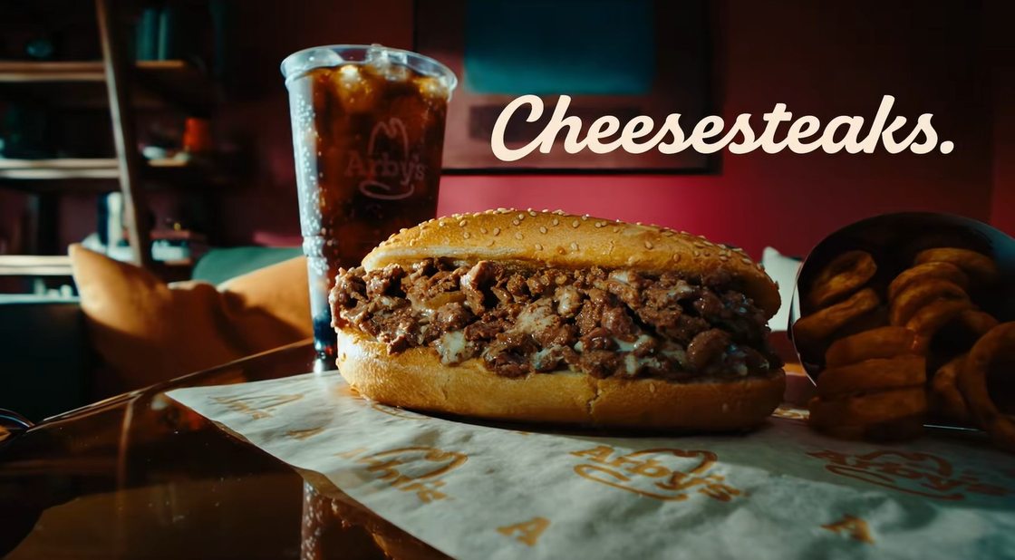 Arby’s Angus Cheesesteak with a drink and curly fries