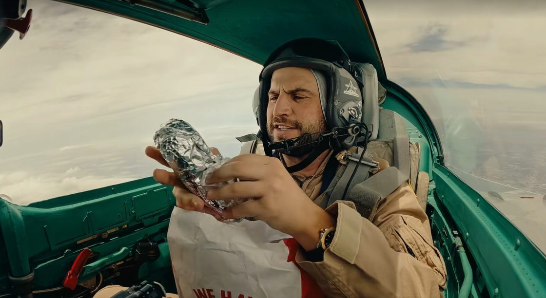 Robby Berger unwrapping a foil-wrapped Arby’s cheesesteak in the MiG-21 cockpit