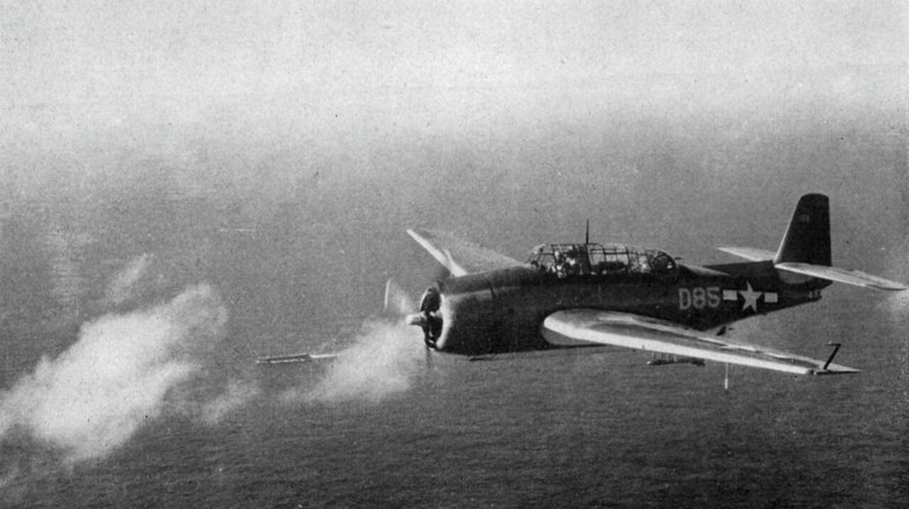 A U.S. Navy Grumman TBF Avenger over an escort carrier in 1944