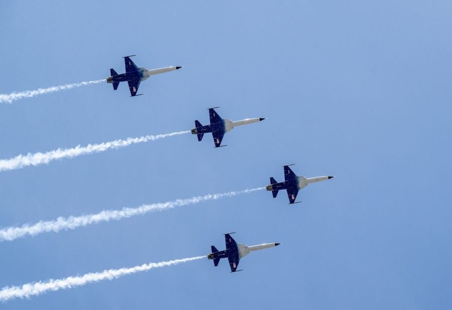Cuatro aviones F-5 de la NASA en formación cerrada dejando una estela de humo.