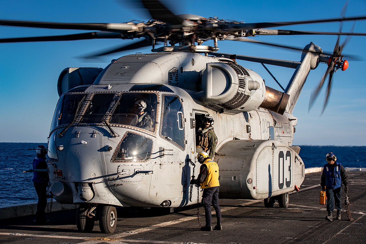 Sailors working around a CH-53K King Stallion during sea trials aboard USS Arlington