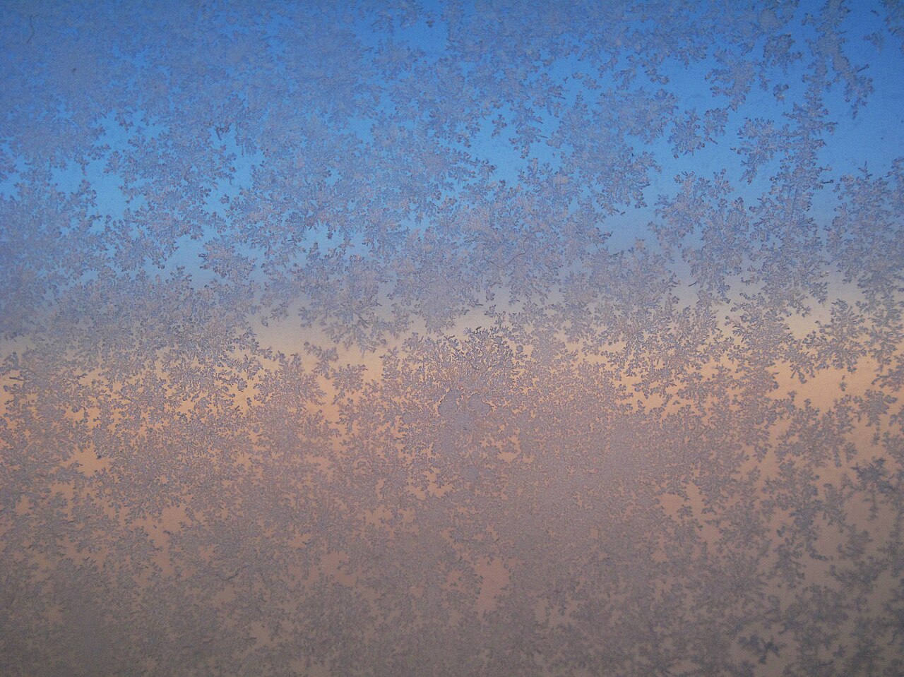 Motifs de givre sur une vitre de cabine d'avion en altitude