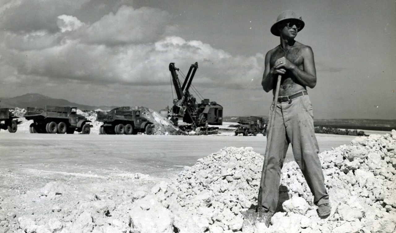 A Seabee directs trucks unloading coral for a B-29 runway on Tinian