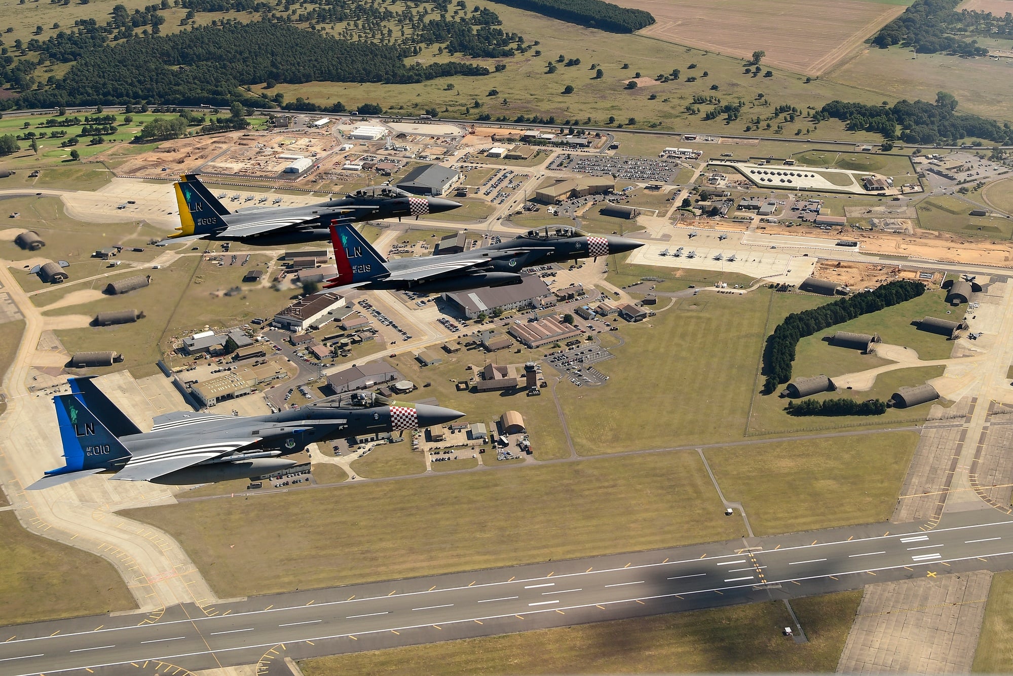 Two F-15E Strike Eagles and an F-15C Eagle of the 48th Fighter Wing in squadron heritage colours over RAF Lakenheath