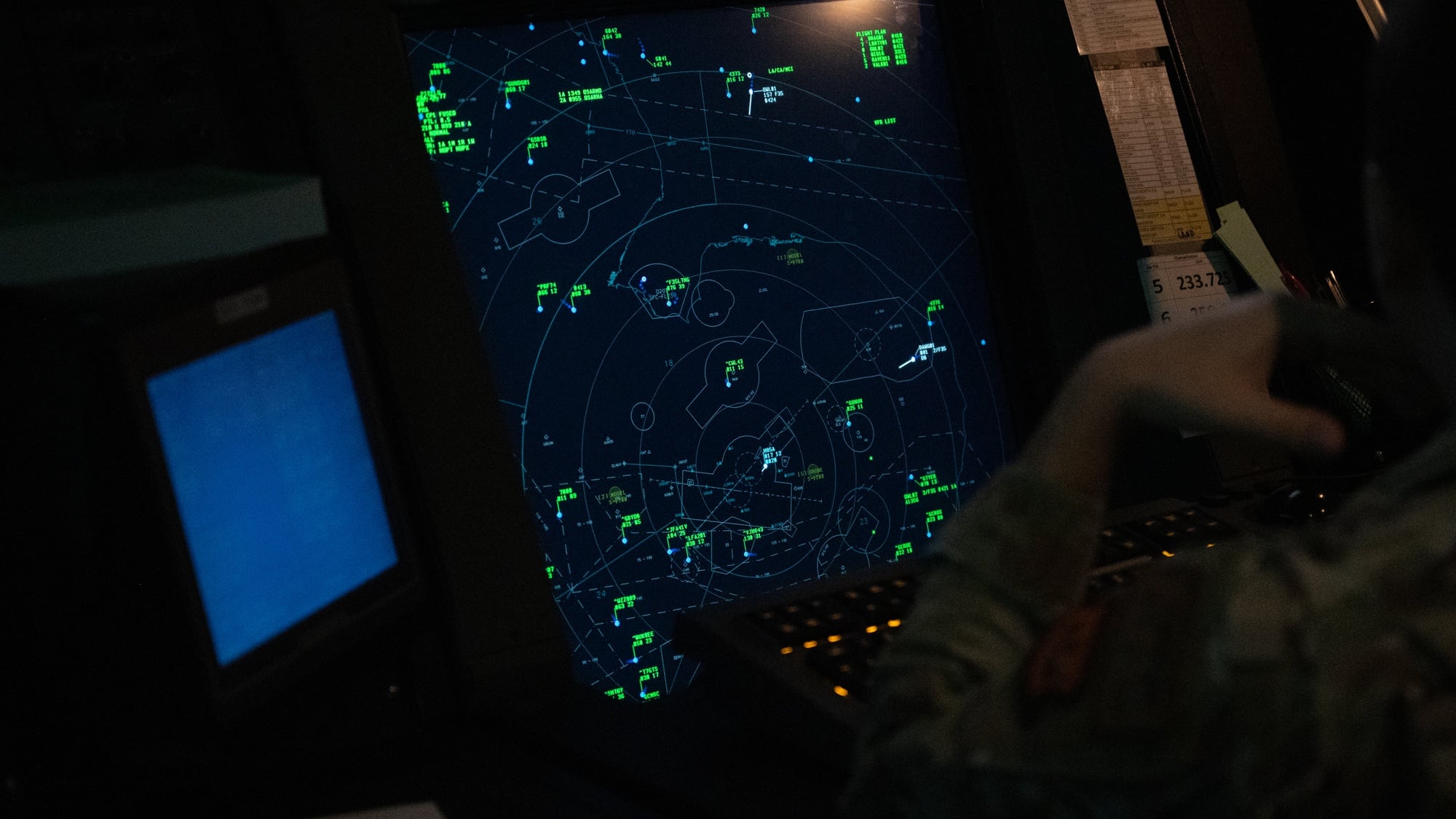 An air traffic controller watches a radar scope in a darkened radar approach control room