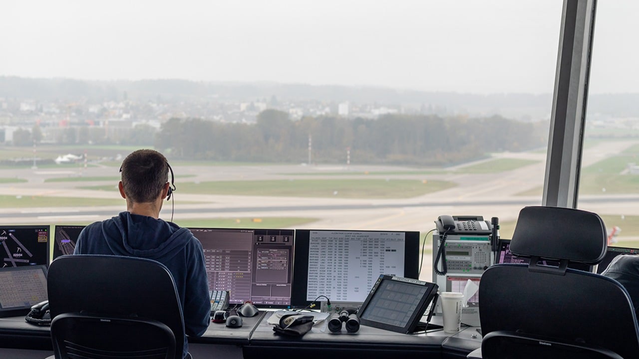 An air traffic controller working at a radar and flight-strip position in an airport tower cab