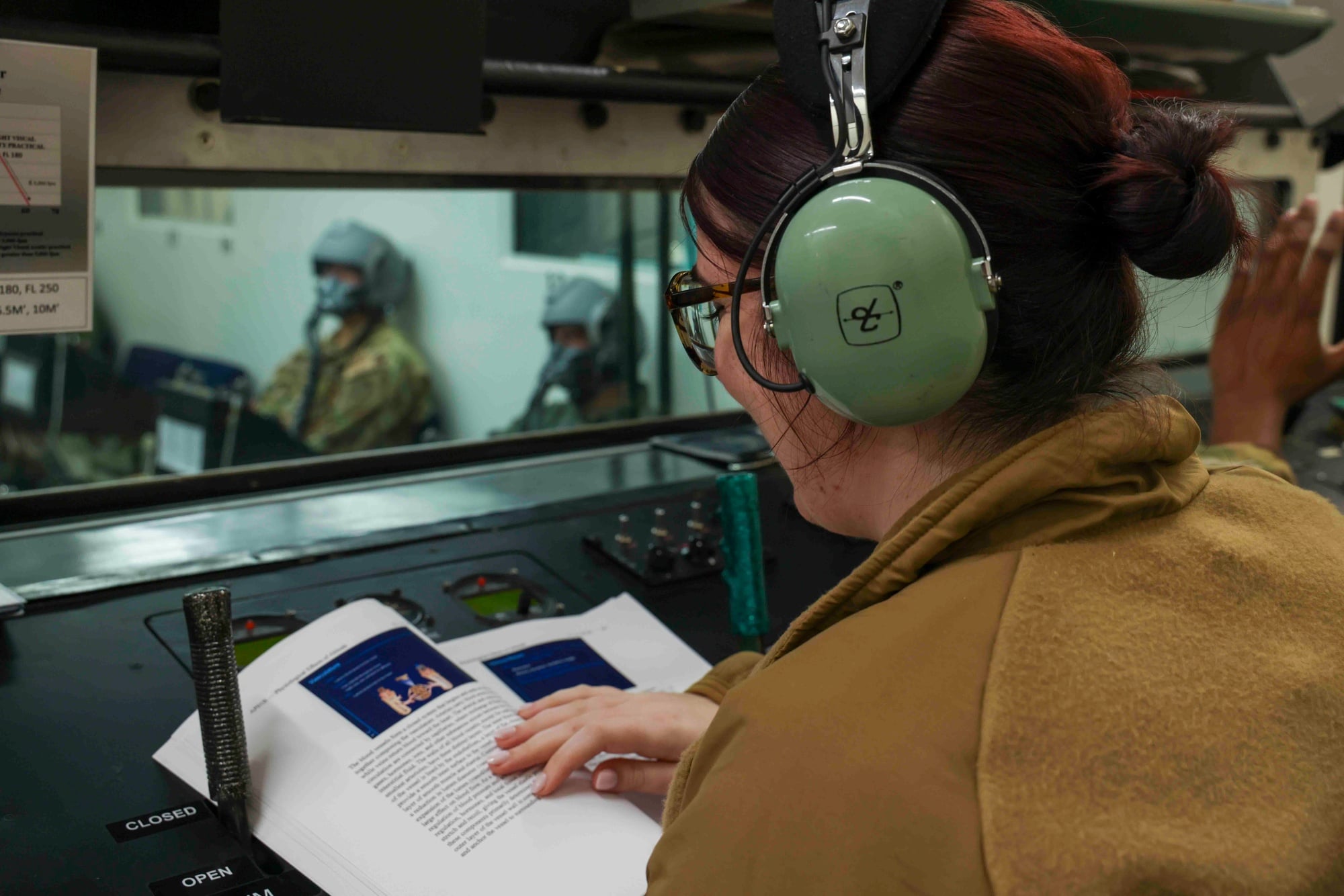 An altitude chamber operator works the profile from the console while students sit inside the chamber
