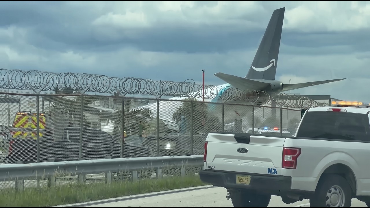 The Amazon-liveried Boeing 767 tail visible beyond the airport perimeter fence at Miami after the runway overrun on 6 September 2026