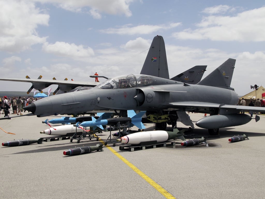 An Atlas Cheetah fighter of the South African Air Force on static display with an array of bombs and missiles laid out in front of it