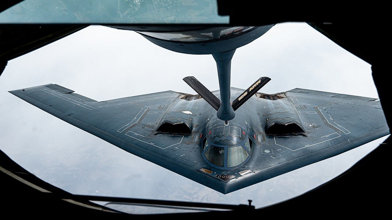 A B-2 Spirit flying behind a KC-135 Stratotanker