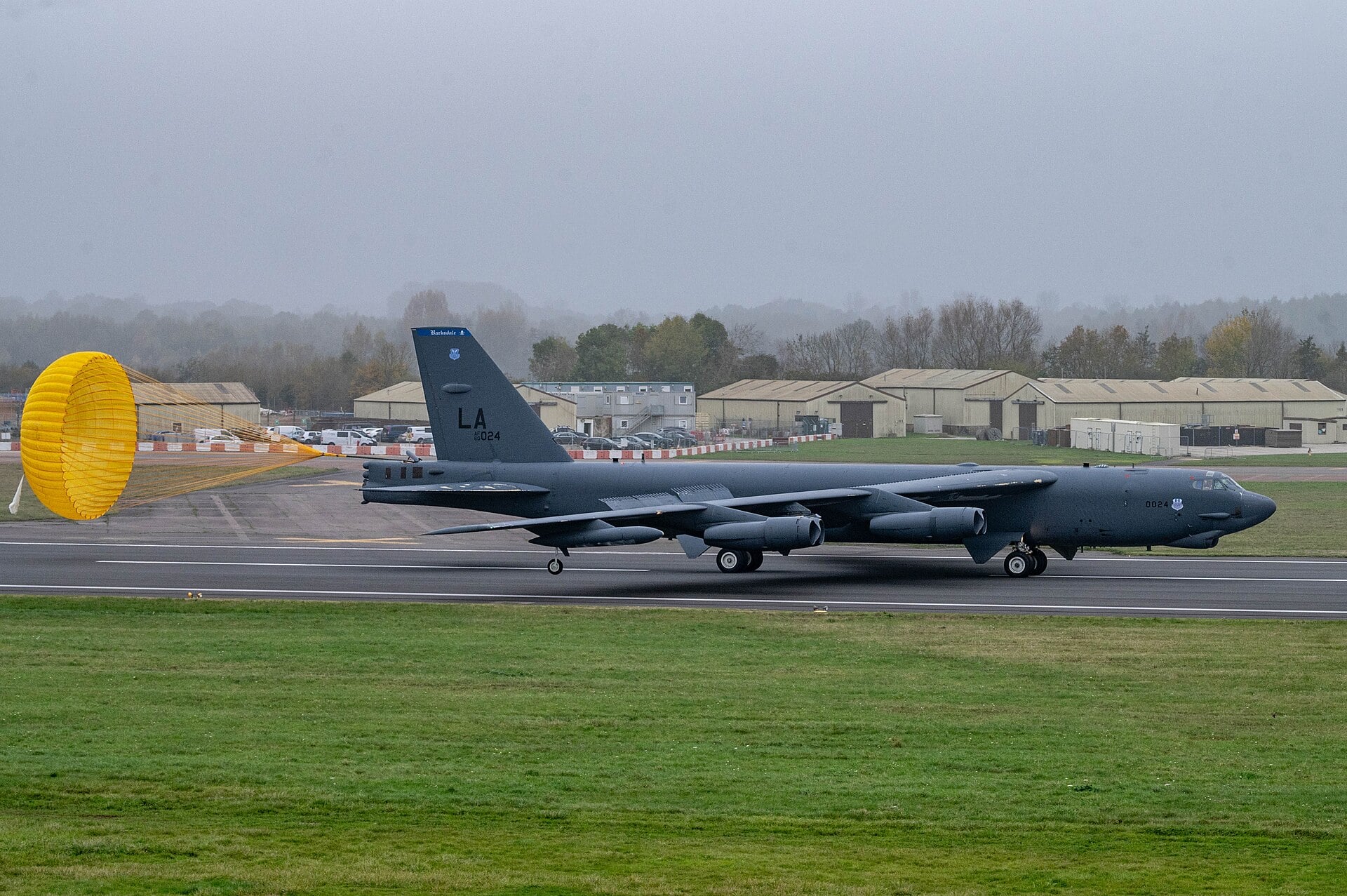 A B-52H Stratofortress rolling out on the runway with its yellow drag parachute deployed