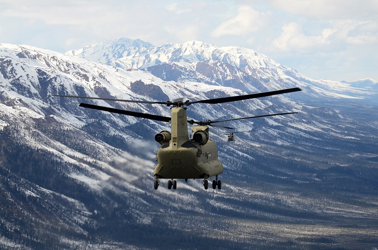 A US Army Boeing CH-47F Chinook flying over snow-covered mountains during a delivery flight