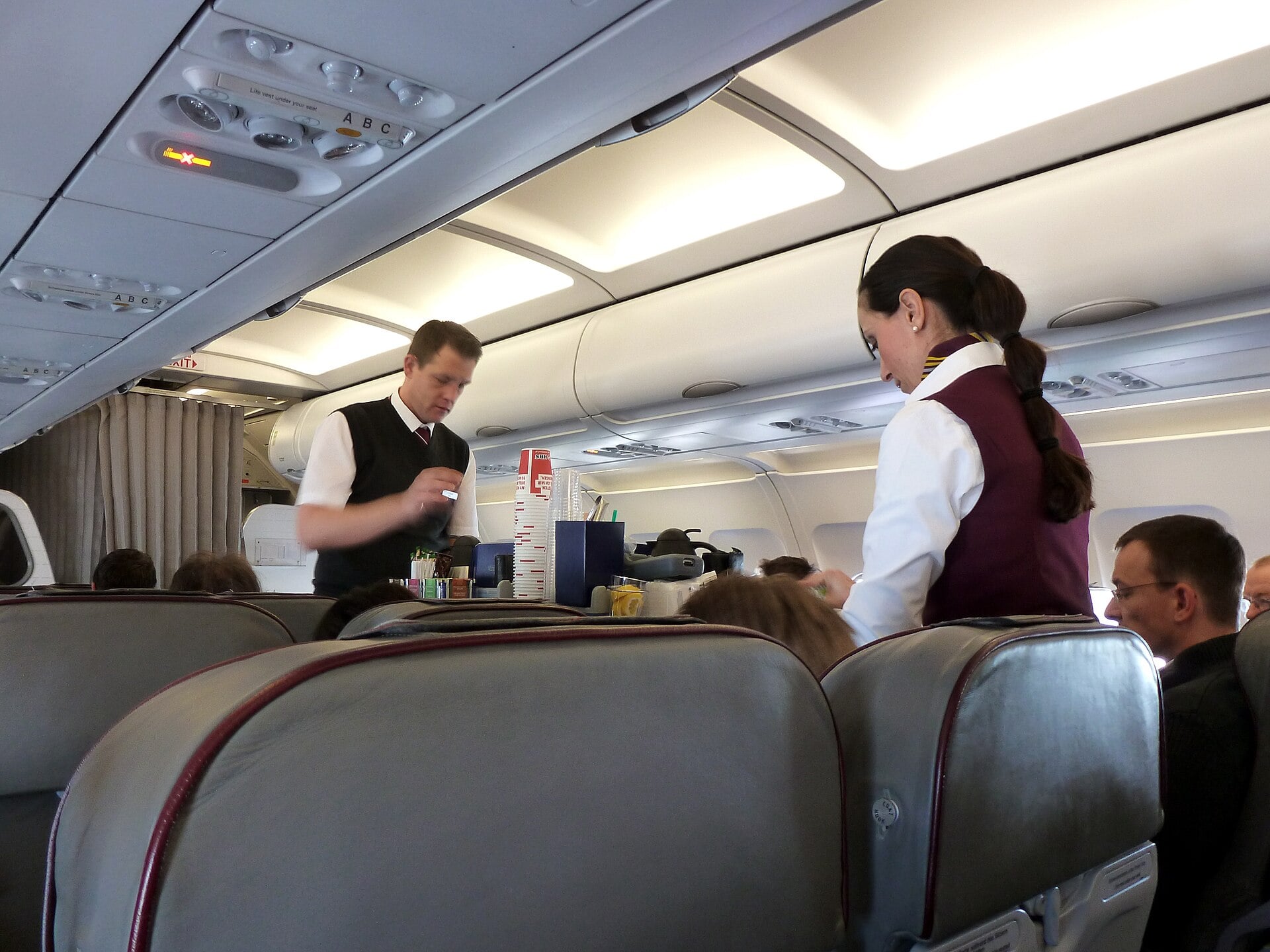 Cabin crew working a trolley service in an airliner cabin during flight