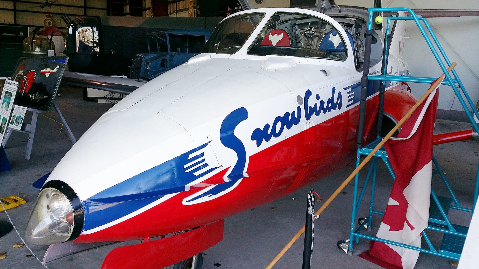 The nose of a Canadair CT-114 Tutor in Snowbirds markings inside a hangar