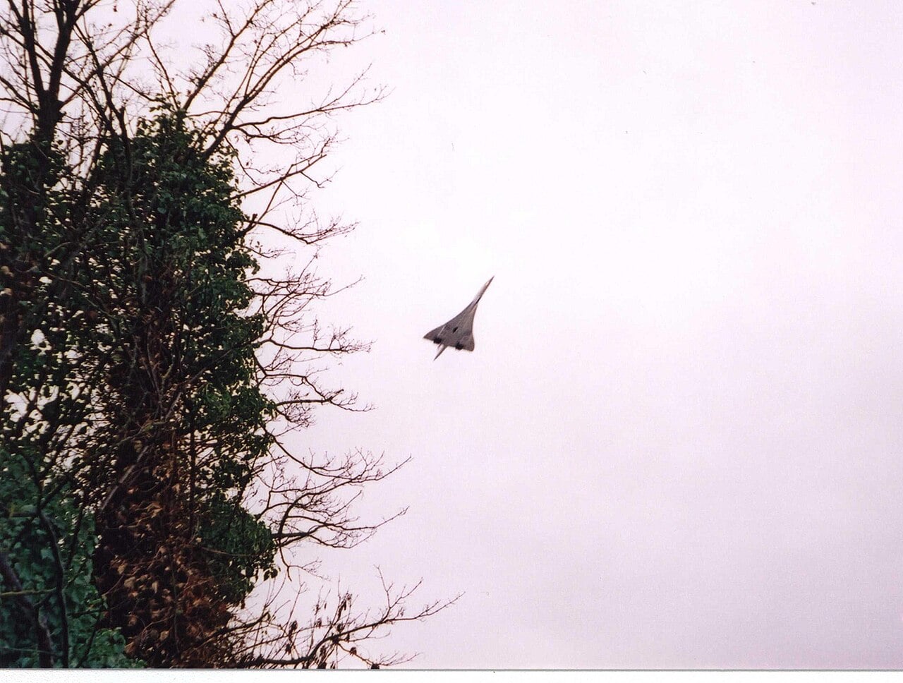 Concorde seen in silhouette against a grey sky on its final approach into London Heathrow