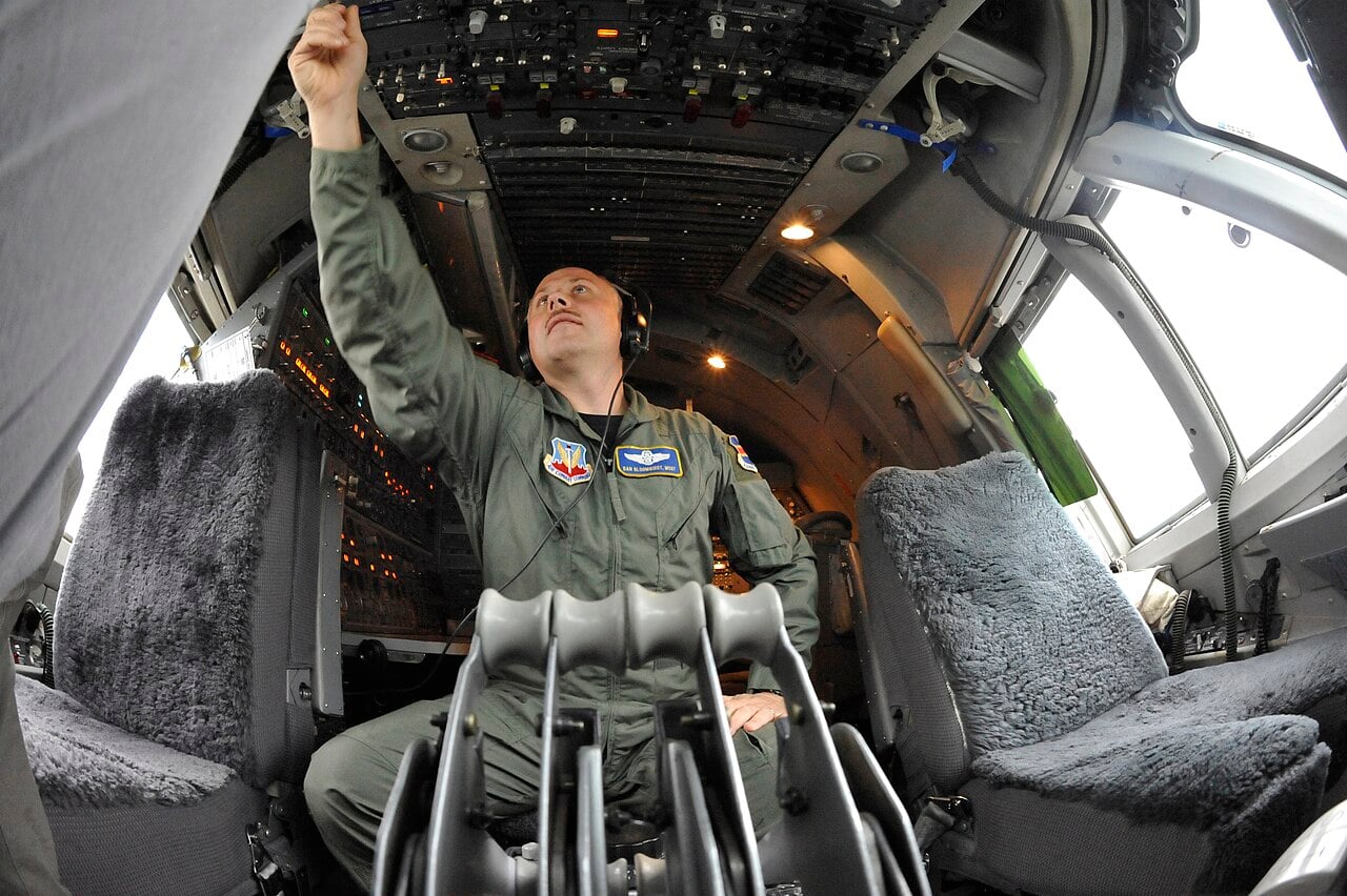 Flight engineer preparing the E-4B cockpit, which retains analogue instruments
