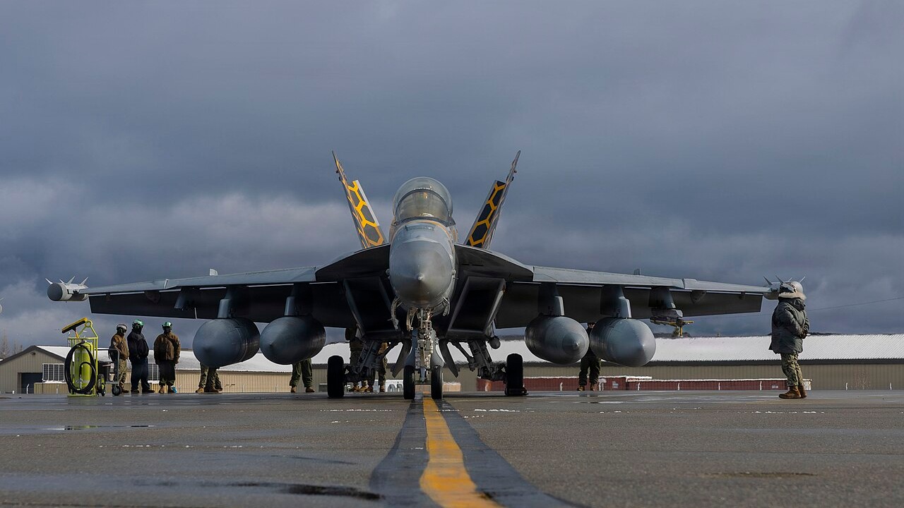 A US Navy EA-18G Growler on a wet apron loaded with jamming pods under its wings and centreline