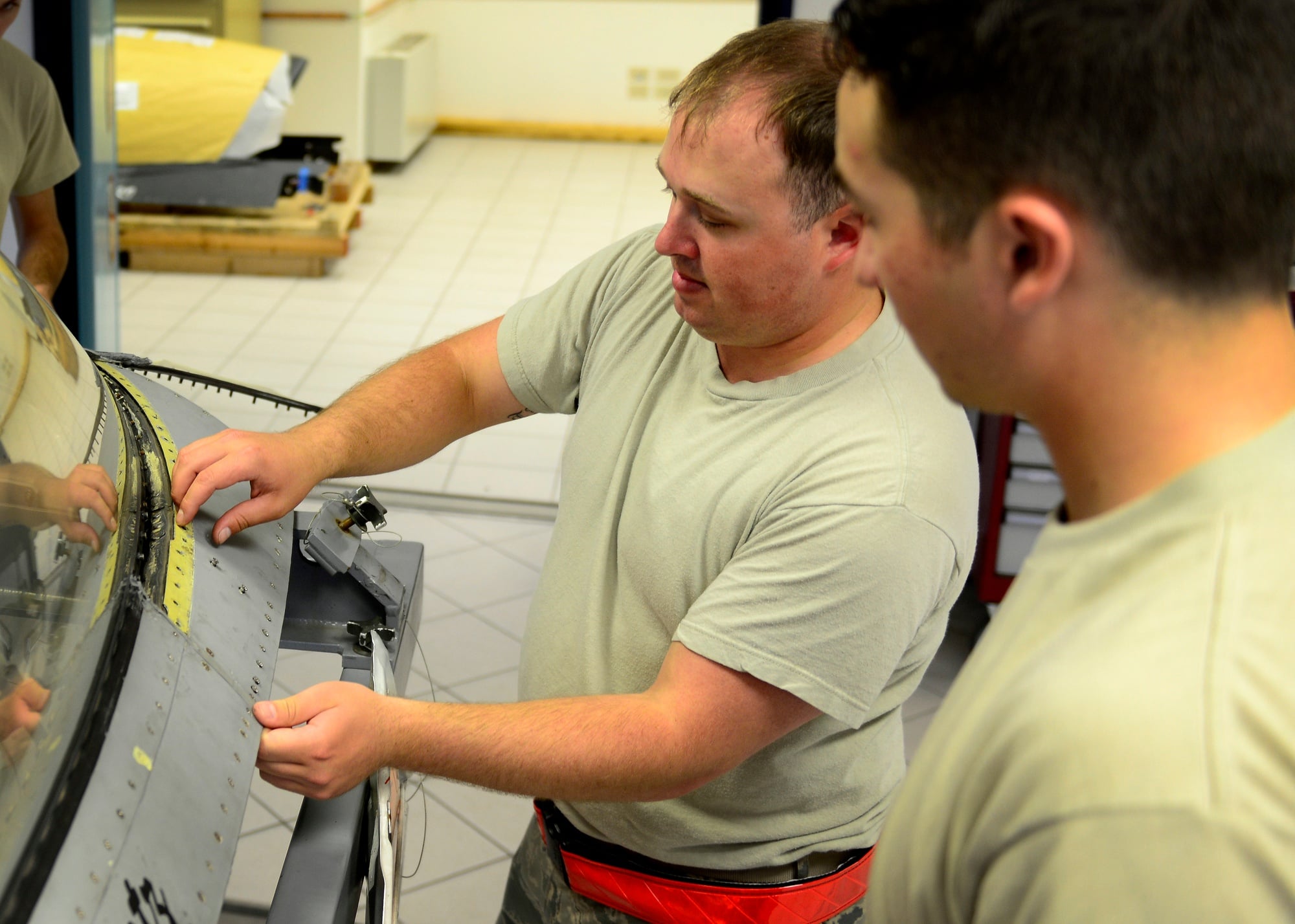 Egress systems technicians remove panels from a jet canopy