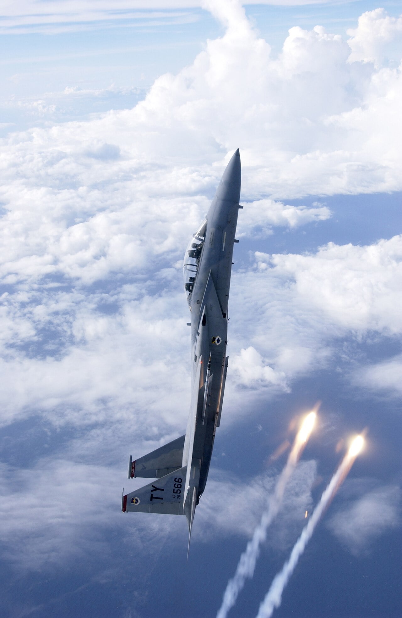 Eine F-15 Eagle steigt senkrecht auf und wirft dabei Leuchtraketen ab.