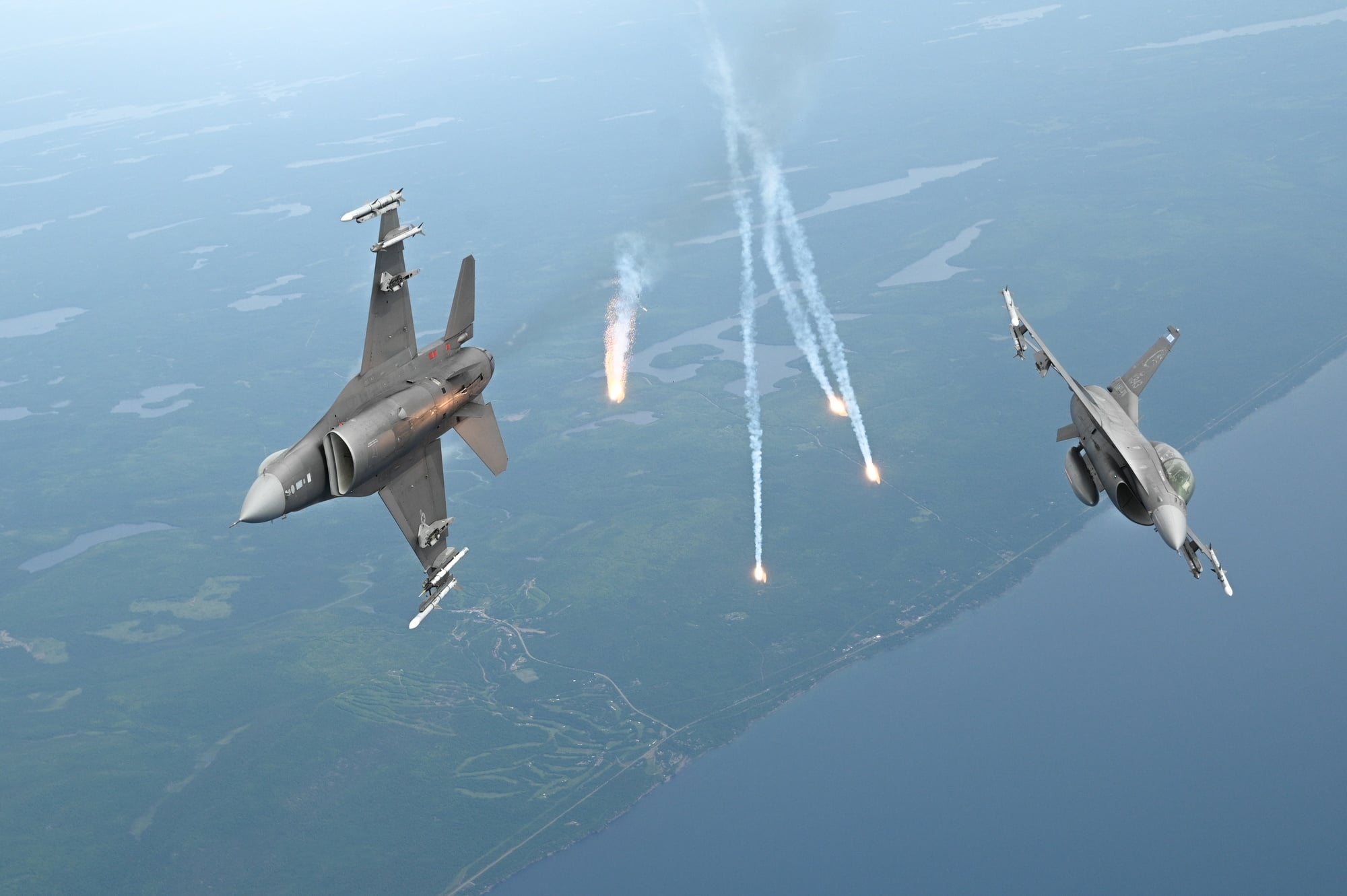 Two F-16 Fighting Falcons of the 148th Fighter Wing dispensing decoy flares in flight