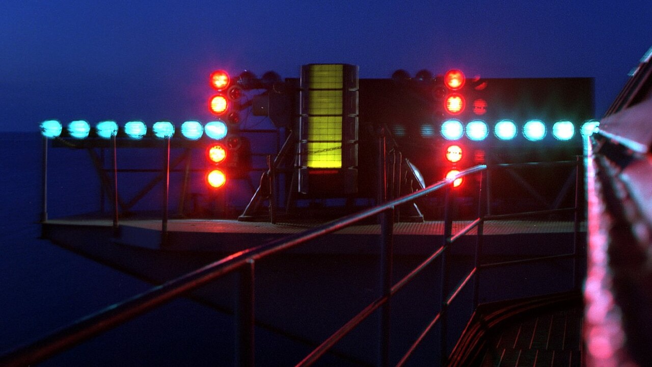 The Fresnel lens optical landing system glowing on the deck edge of an aircraft carrier at night
