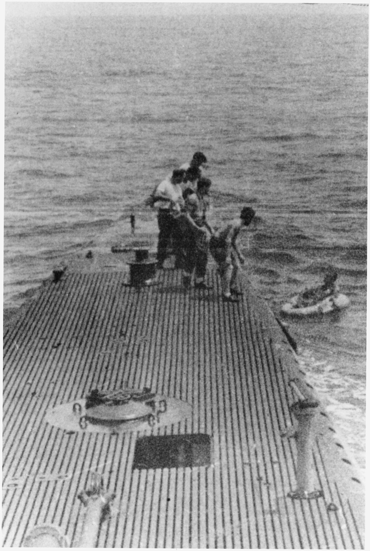 Sailors on the deck of the submarine USS Finback pulling a downed airman aboard, 2 September 1944