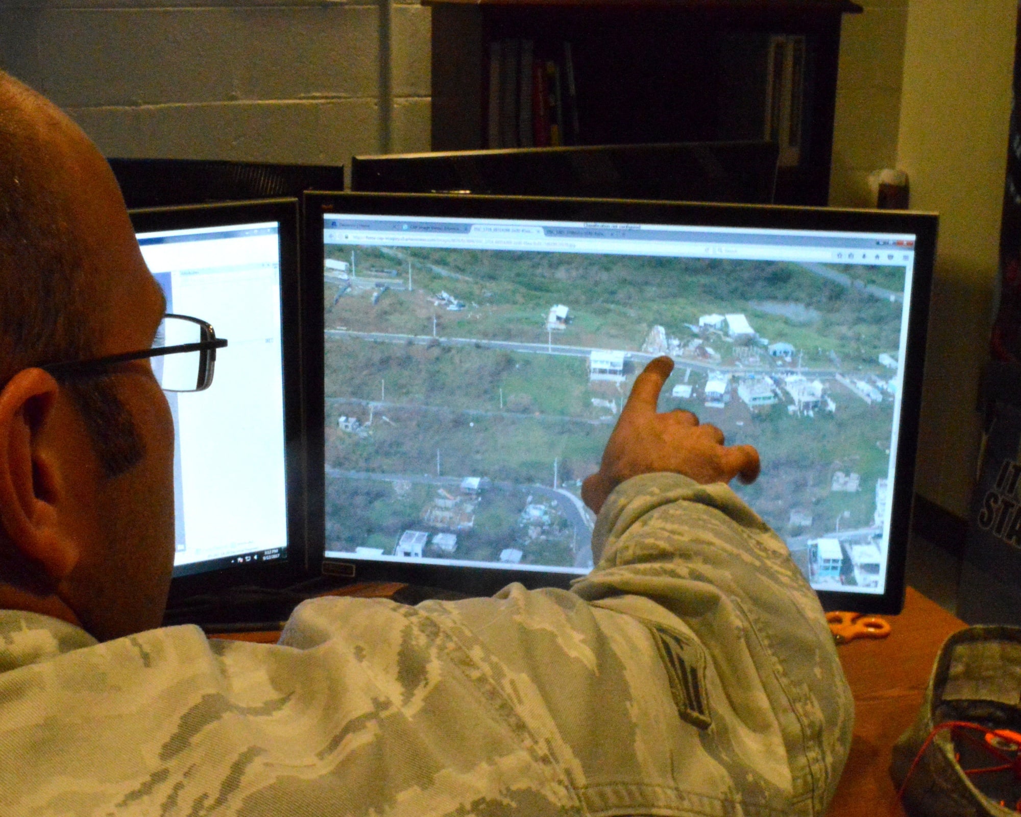 Geospatial analyst points at imagery on screen