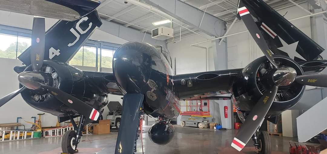 A Grumman F7F Tigercat twin-engined fighter in dark blue US Navy markings inside a hangar