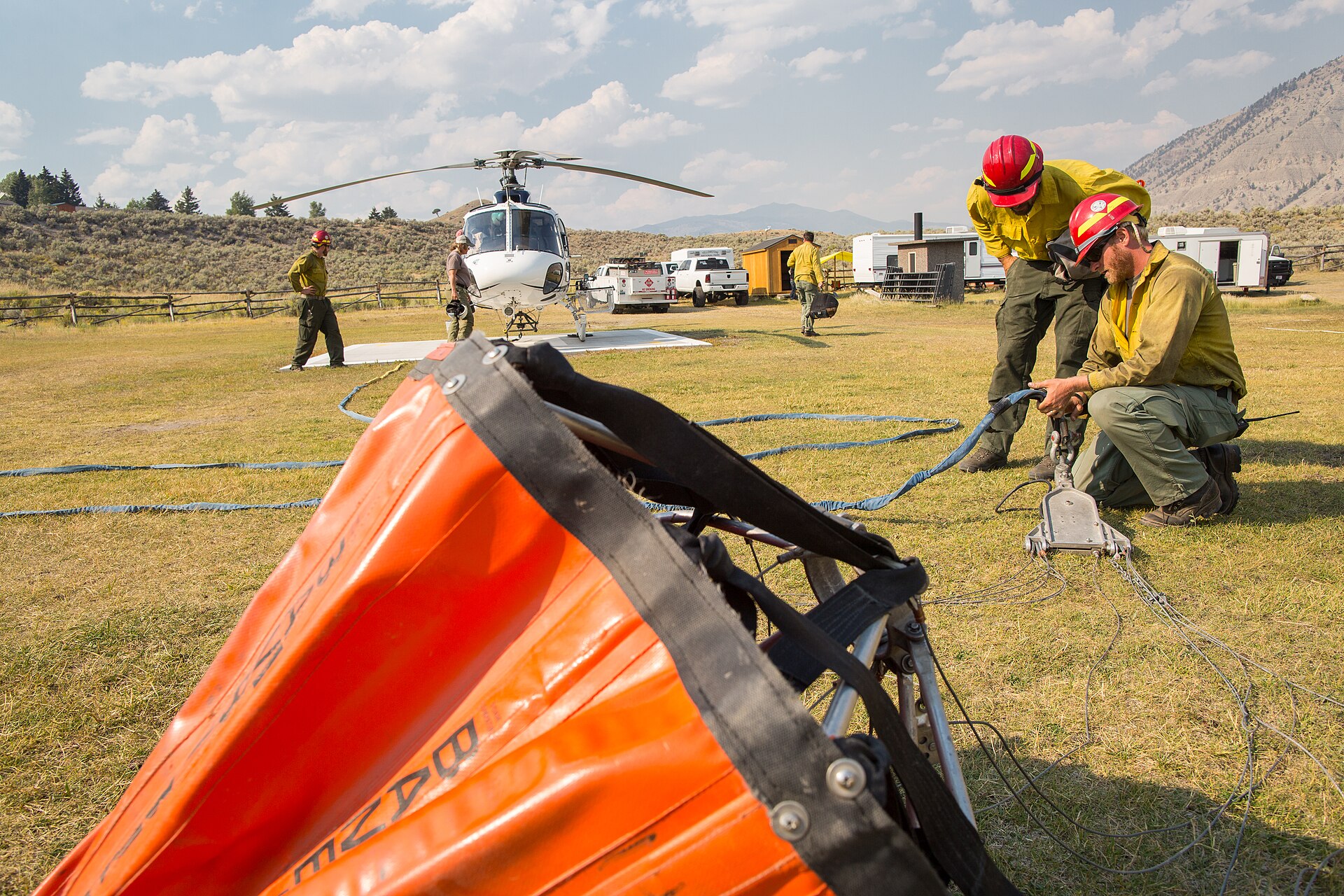 Helitack crew members rigging a helicopter water bucket