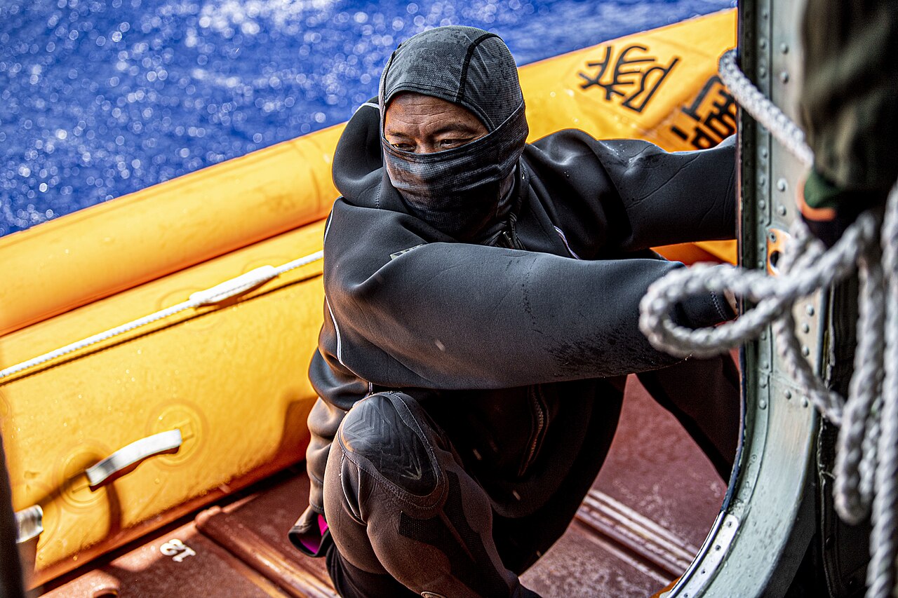 JMSDF rescue swimmer holding onto the hull of a US-2 at sea