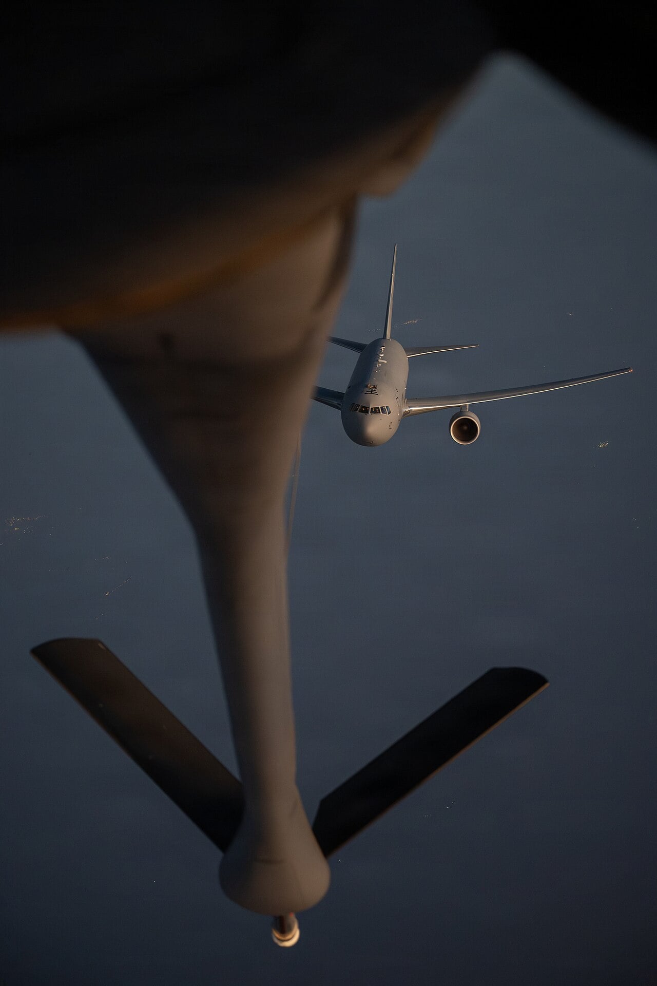 A US Air Force KC-46 Pegasus approaches the refuelling boom of a KC-135 Stratotanker at dusk