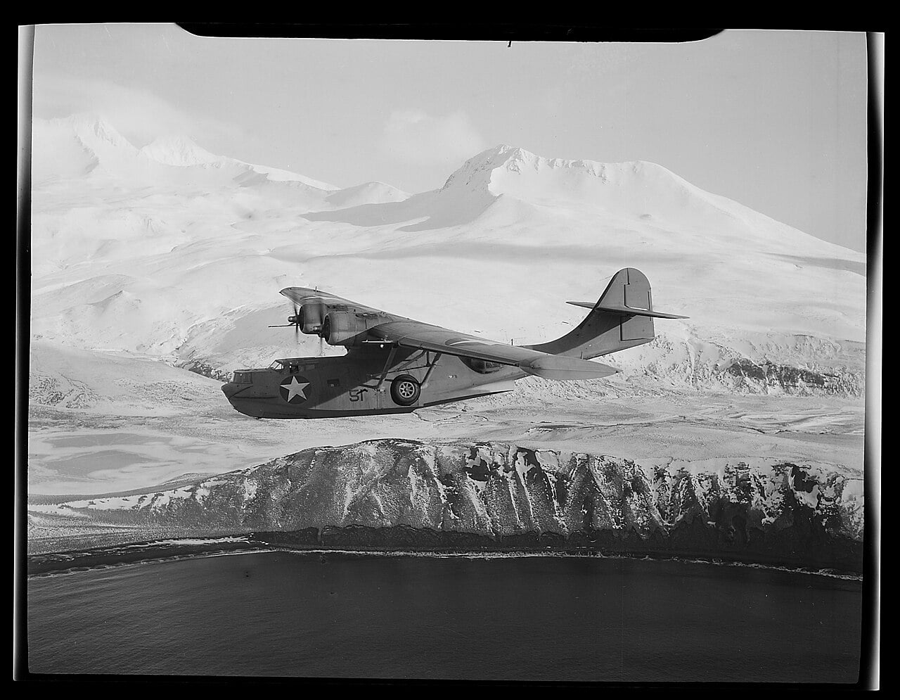 A PBY-5A Catalina over the snow-covered mountains of the Aleutian Islands A PBY-5A Catalina over the snow-covered mountains of the Aleutian Islands