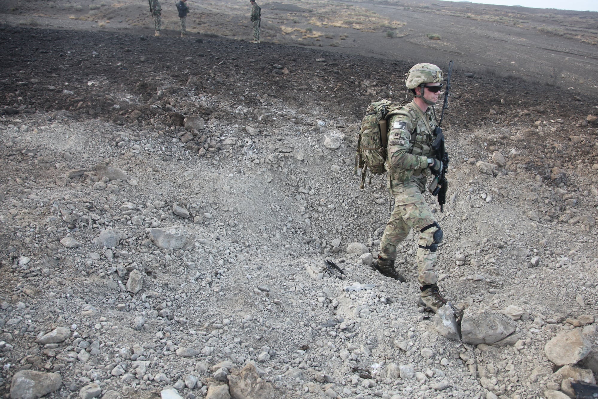 Soldier stands in a crater during battle damage assessment
