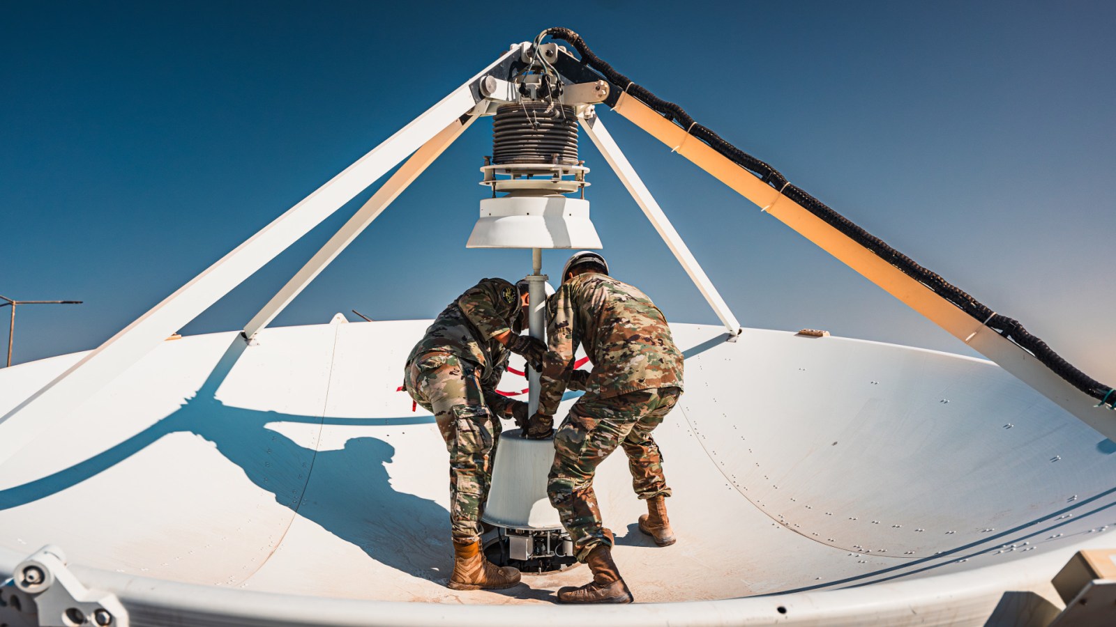 Space Force Guardians working on the feed assembly of a large dish antenna in the Middle East