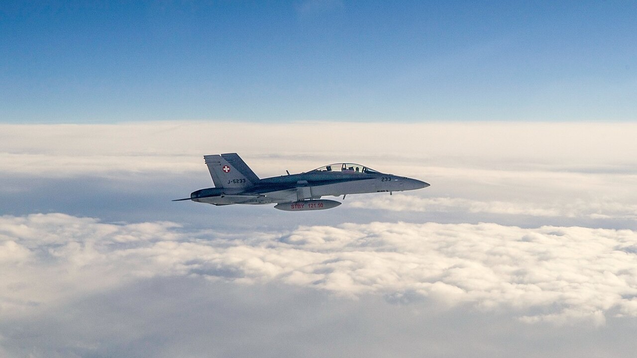 A Swiss Air Force F/A-18C Hornet flying alongside another aircraft