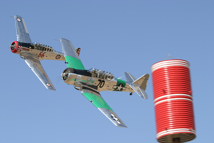 Two T-6 Texan air racers banking hard around a red and white course pylon