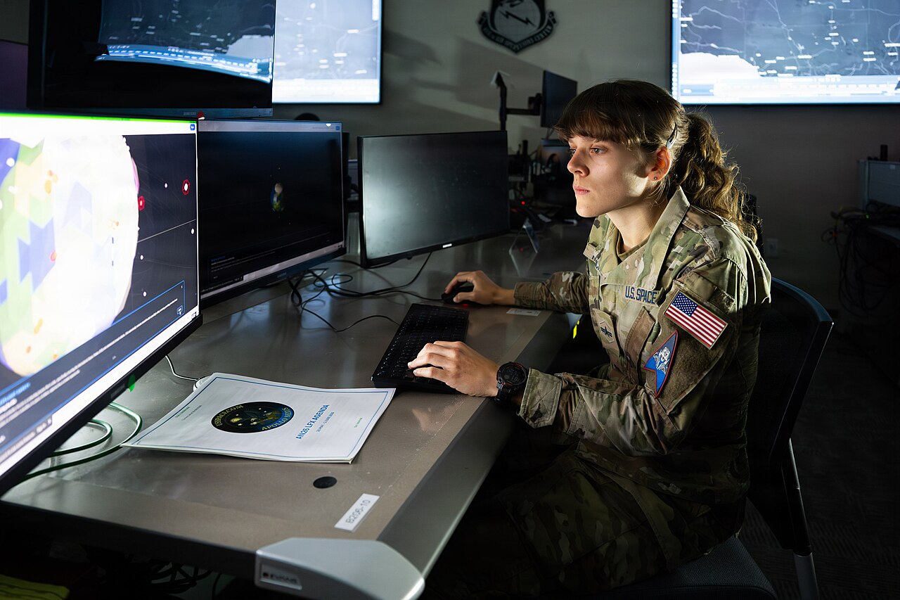 A US Space Force Guardian monitoring space domain awareness displays at a workstation