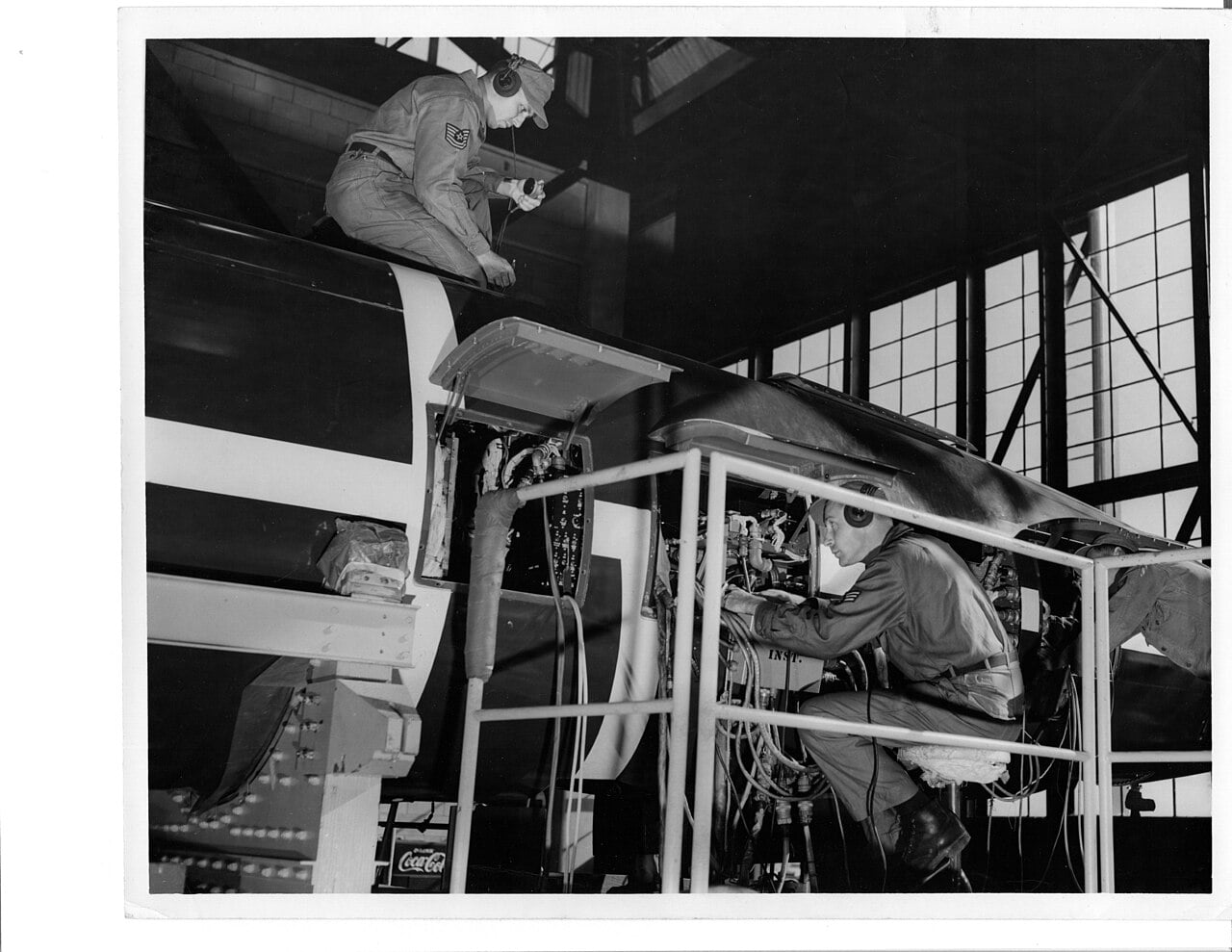 Two US Air Force airmen working on an SM-62 Snark missile inside a hangar in 1957