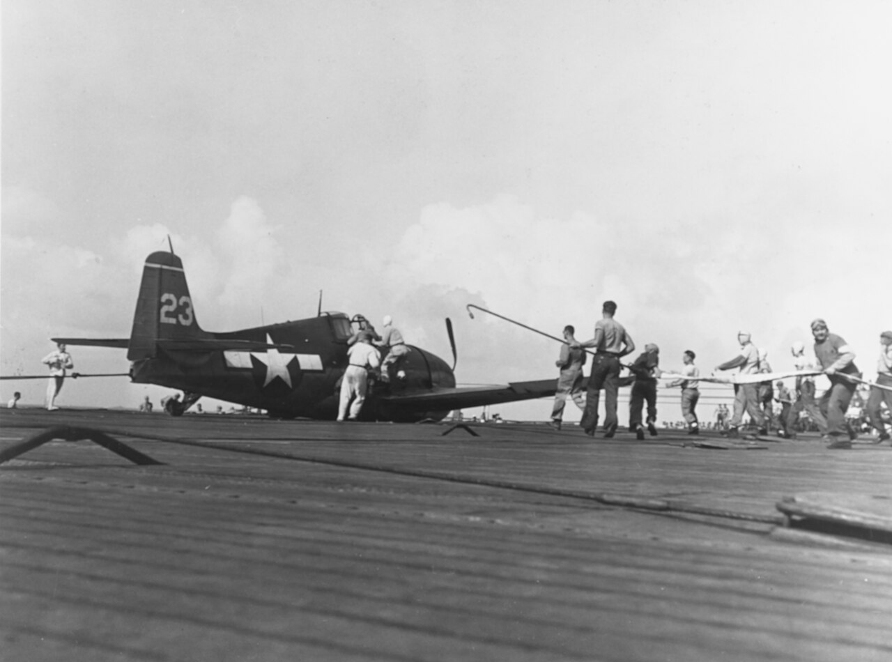 Flight deck crew aboard USS Essex attending a damaged VF-15 Grumman F6F Hellcat after a crash landing