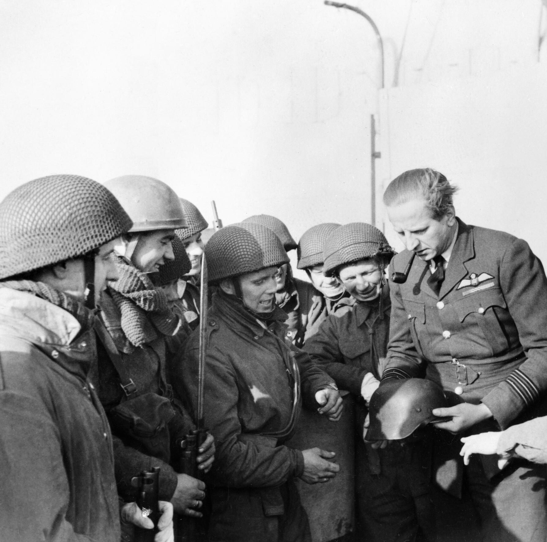 Wing Commander Percy Pickard of No. 51 Squadron RAF inspects a captured German helmet with paratroopers after the Bruneval raid