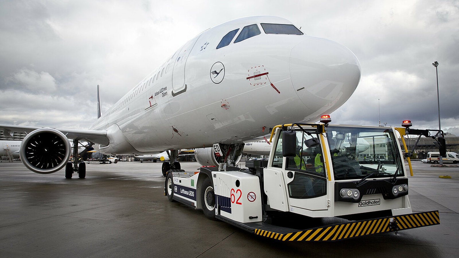 Goldhofer Phoenix E electric towbarless tug lifting the nose gear of a Lufthansa Airbus A321neo for aircraft pushback