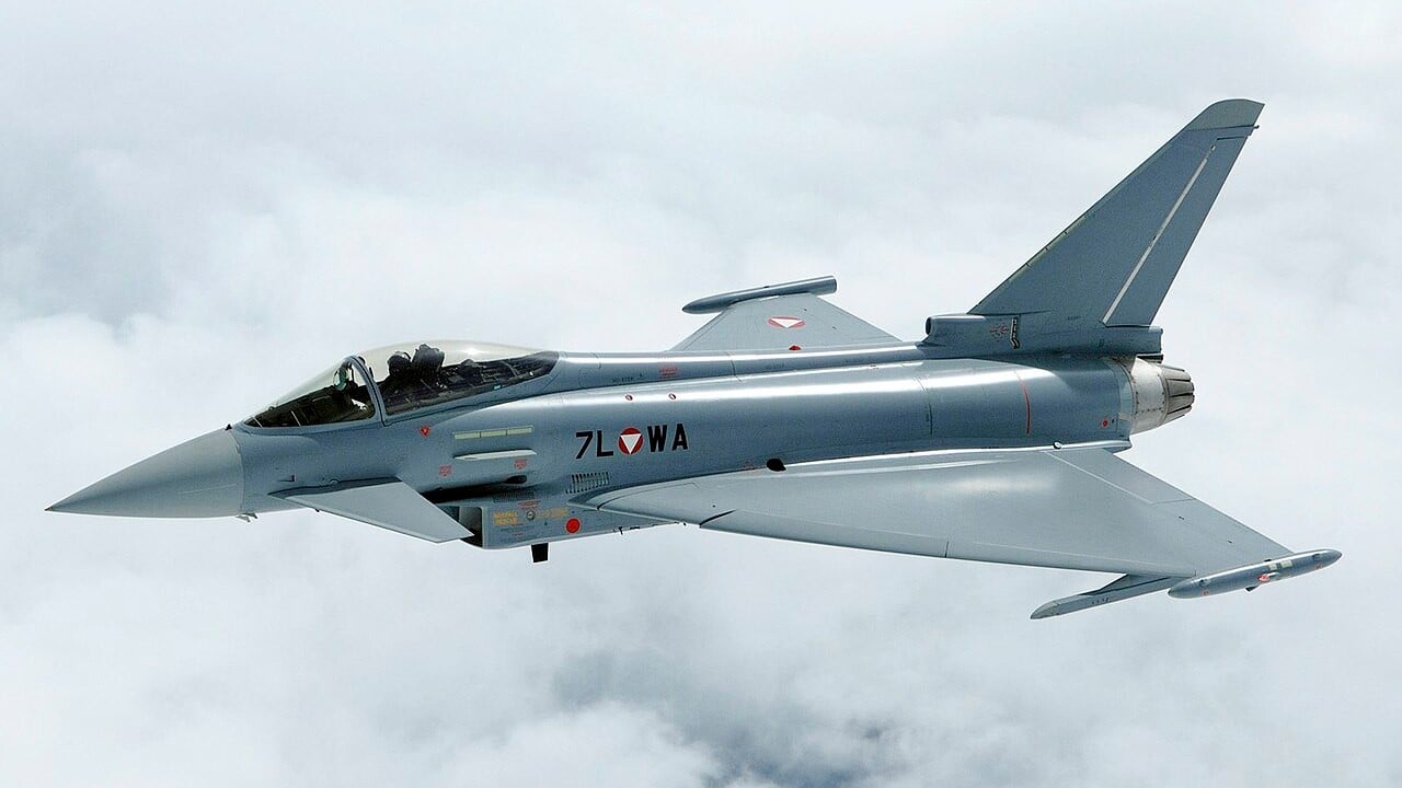 A grey Austrian Air Force Eurofighter Typhoon in flight above clouds