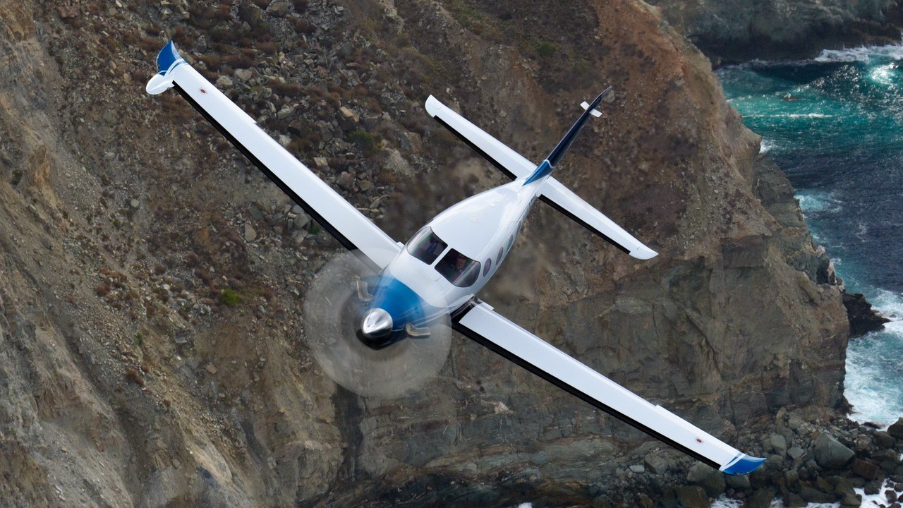 Epic E1000 AX single-engine turboprop banking over a rocky coastline