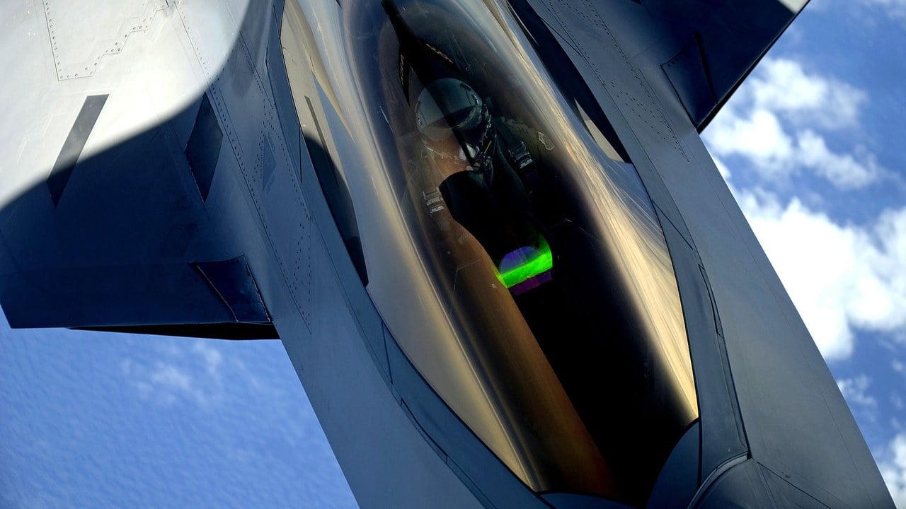 Gold-tinted canopy of a US Air Force F-22 Raptor seen from above during air refuelling, with the pilot visible beneath it