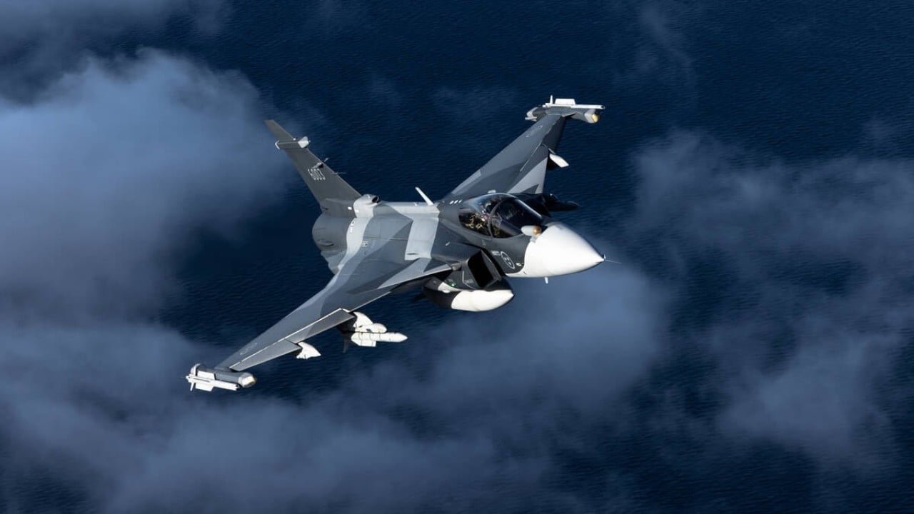 Saab Gripen E in flight A grey Saab Gripen E banking over the sea with missiles on its wingtips