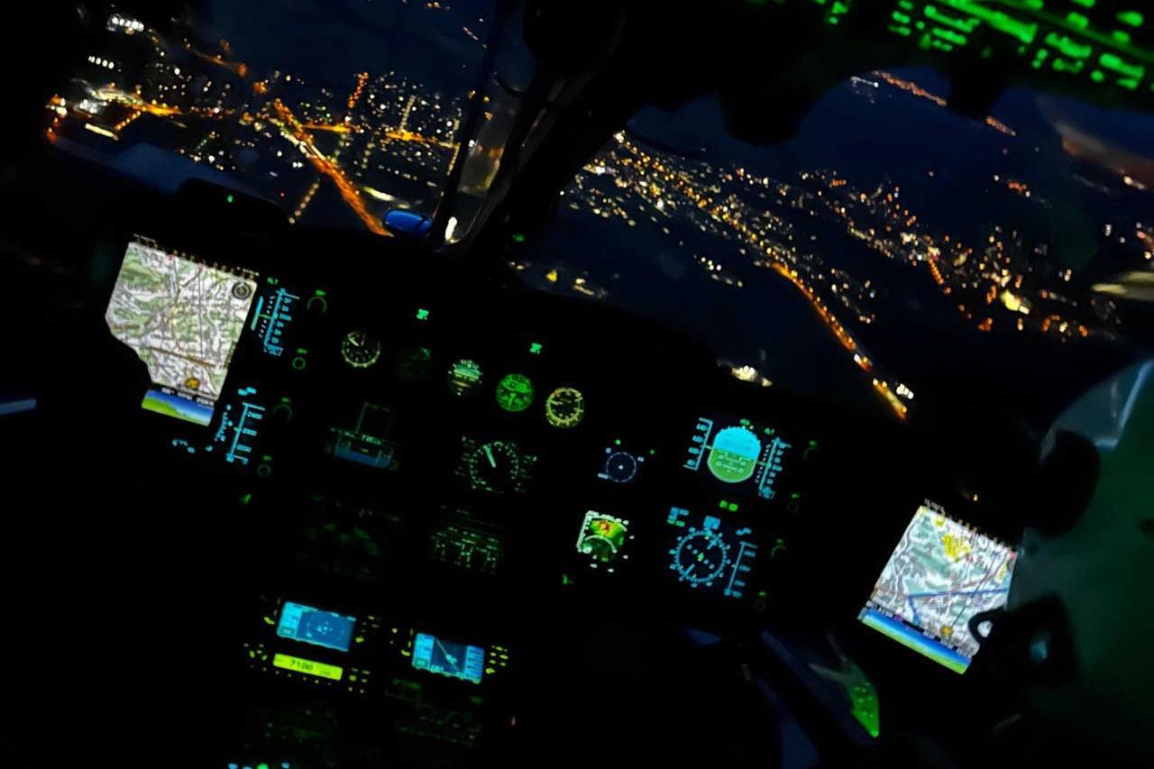 Night view from an AAA Alpine Air Ambulance helicopter cockpit with lit instruments and town lights below