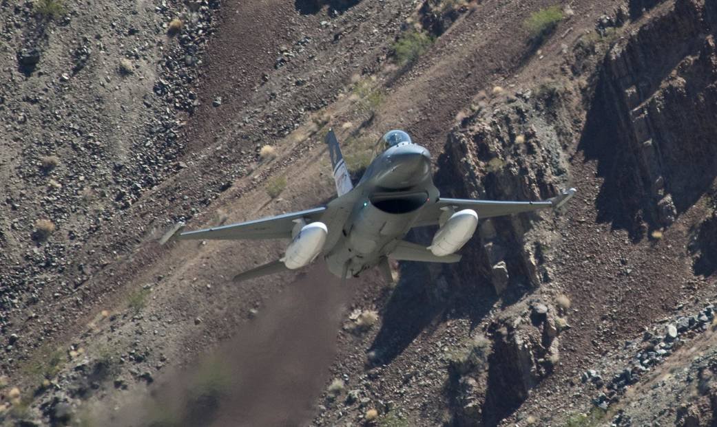US Air Force ACAT F-16D test aircraft flying low through a rocky Sierra Nevada canyon